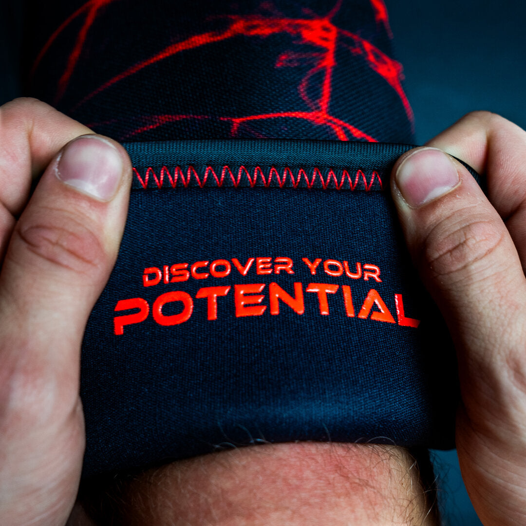 Røde Unlisted Strength knee sleeves bliver påført ben med teksten 'discover your potential' på indersiden
