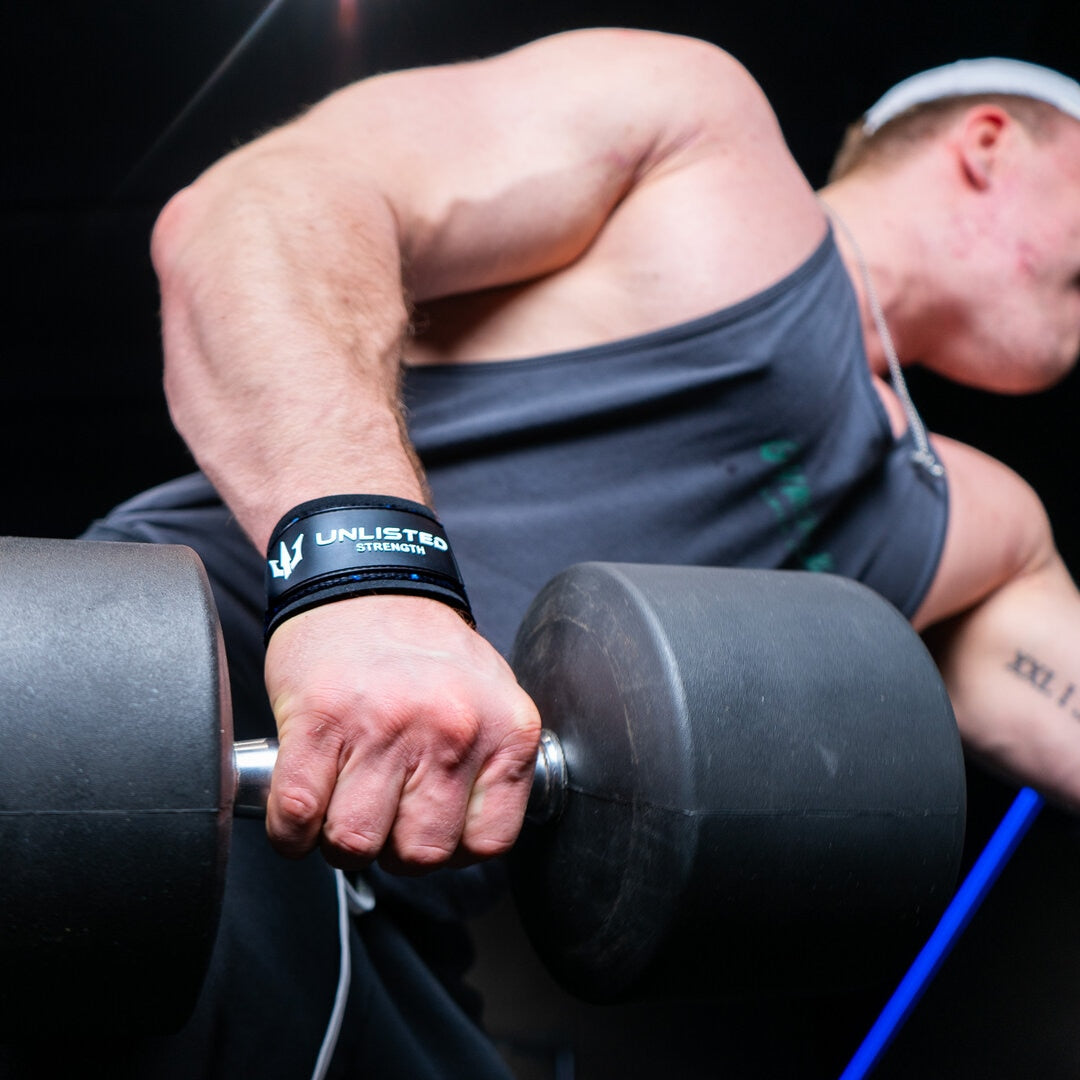 En mand med blå lifting straps i fitnesscenteret som løfter en tung dumbbell